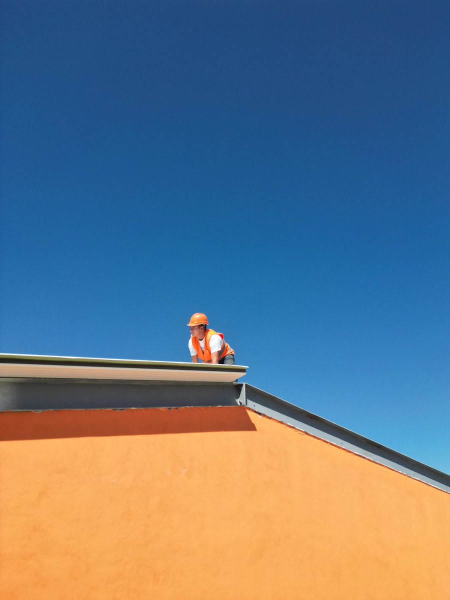 Maestro en el borde de un techo plano bajo cielo azul, impermeabilización de losas en Conchalí